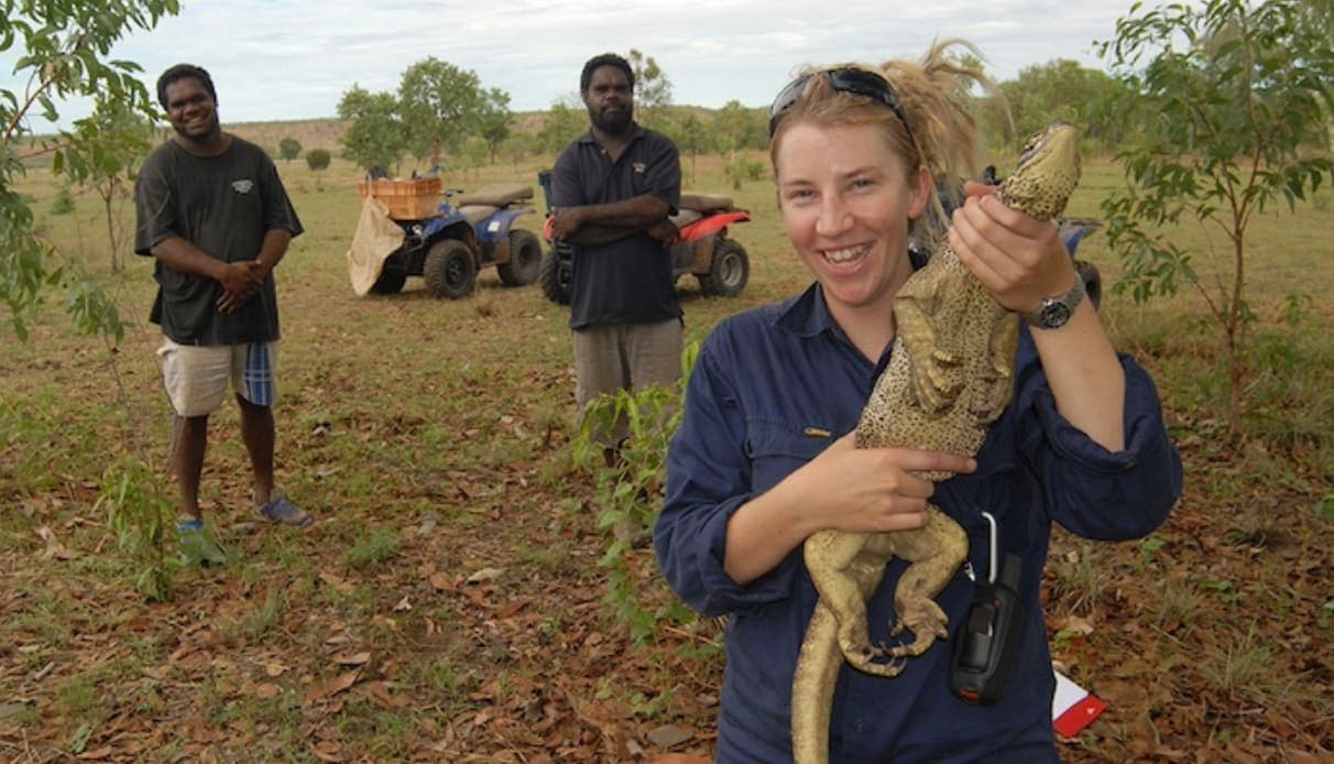 A woman holding a large snake in a field